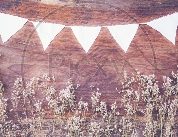 Dry grass and white flags frame on wood background