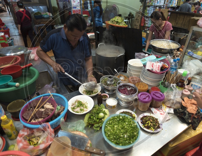 A Street Food Vendor Preparing fast food At a Stall