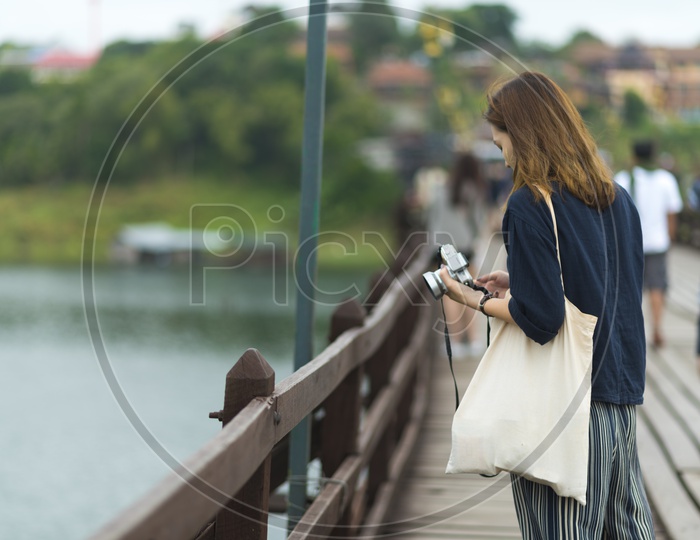 Tourist Woman With Camera In Hand At Wooden bridge