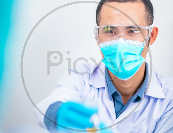 Research Scientist Performing Experiments In Laboratory  Wearing an Apron and Mask