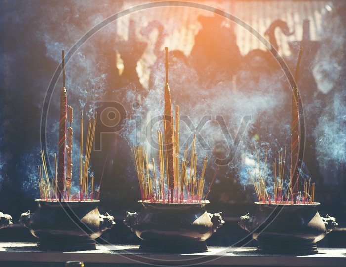 Incense Sticks Burning With Smoke Patterns In Buddhist Temple