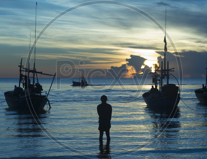 Silhouette Of Fishing Boats And Fisherman Carrying Their Catch Over a River With Blue Hour Sky in Background