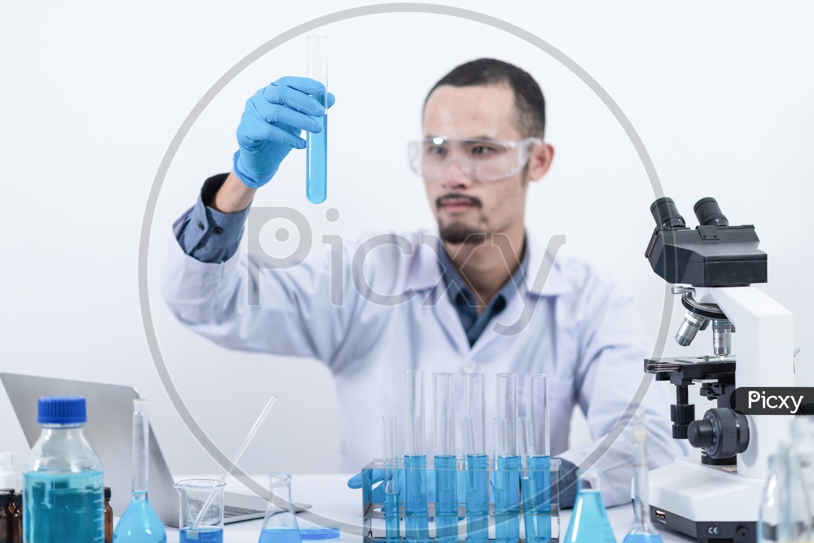 Asian Male Scientist analyzing a sample in test tube at Chemical Laboratory.