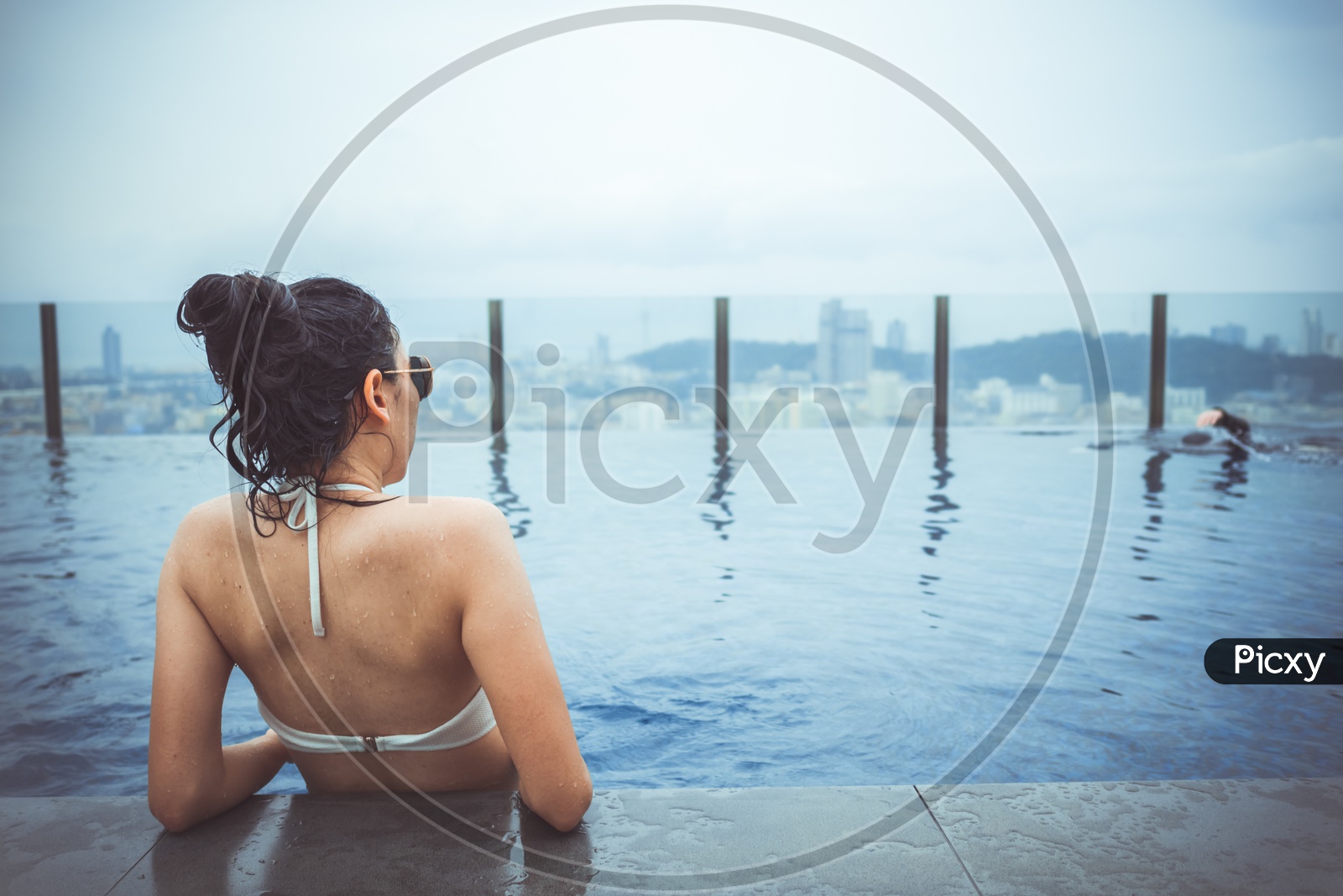 Woman relaxing on a Rooftop Swimming Pool With Pattaya Cityscape
