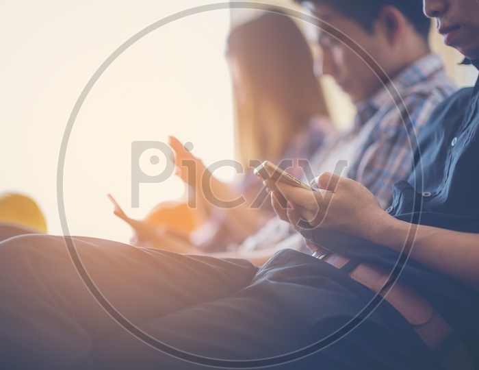 Closeup of people sitting in office, using mobile phones