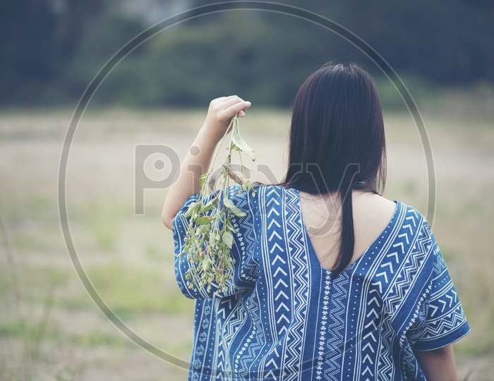 Alone Woman Walking In a Nature with Leafs In hand Wearing Summer Outfits