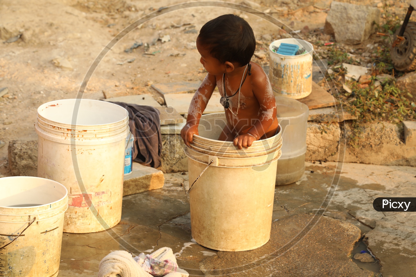 A Child playing with water in a bucket during shower