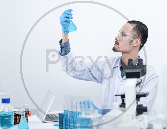 Asian Scientist Analyzing Chemical Liquid Sample in a Test Tube at Laboratory.