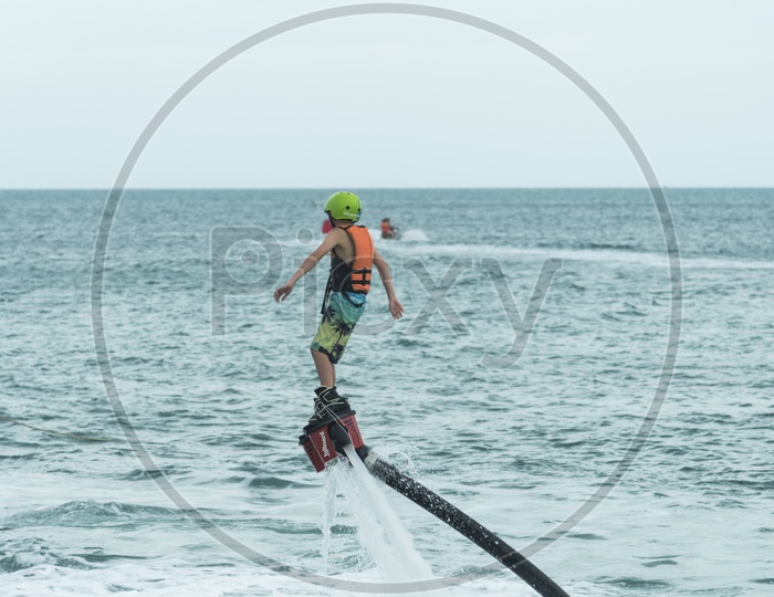 A guy is playing with a new water sport called fly board at bay in Phuket, Thailand