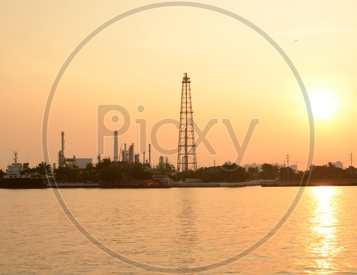 Oil Refinery Silhouette beside a Lake With Sunset Sky In Background