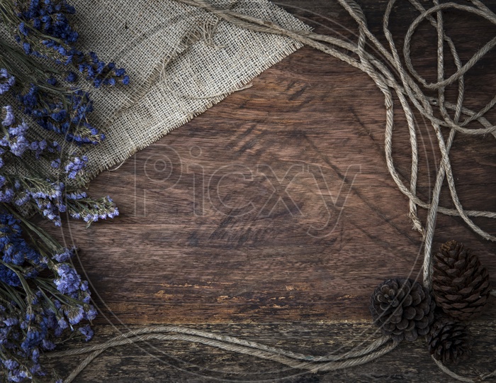 Purple dry flowers and jute threads on wooden board