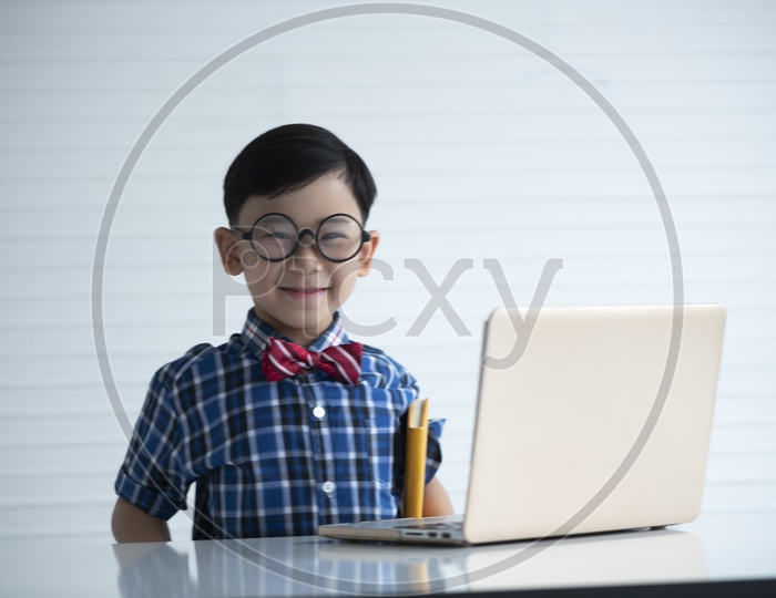 Portrait of a boy wearing spectacles using computers to study