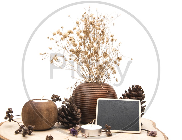 Dried flowers in a wooden vase and candles placed on a wooden table isolated on white background