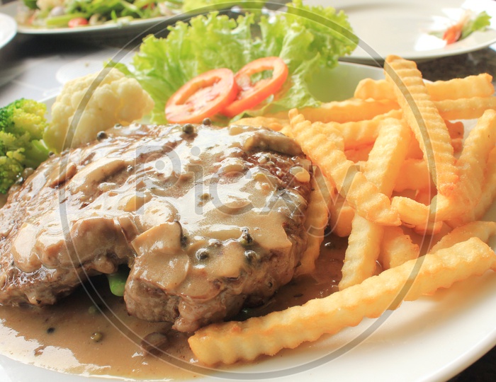Thai Style Grilled Beef steak Garnished with French Fries in a Plate
