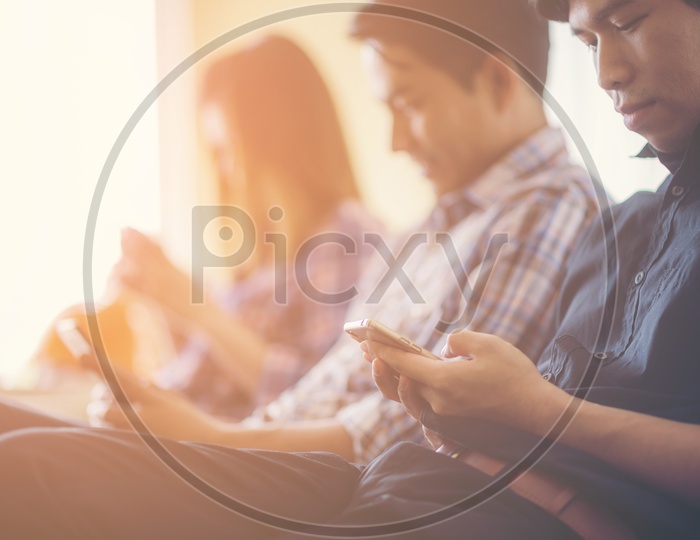 Closeup of Asian man sitting in office, using mobile phones