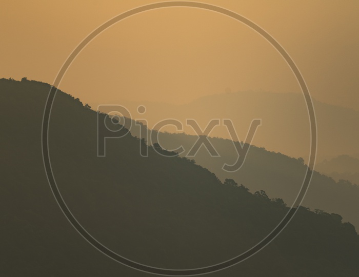 Silhouette Of Mountain Cliff Layers With Sunset Sky Background