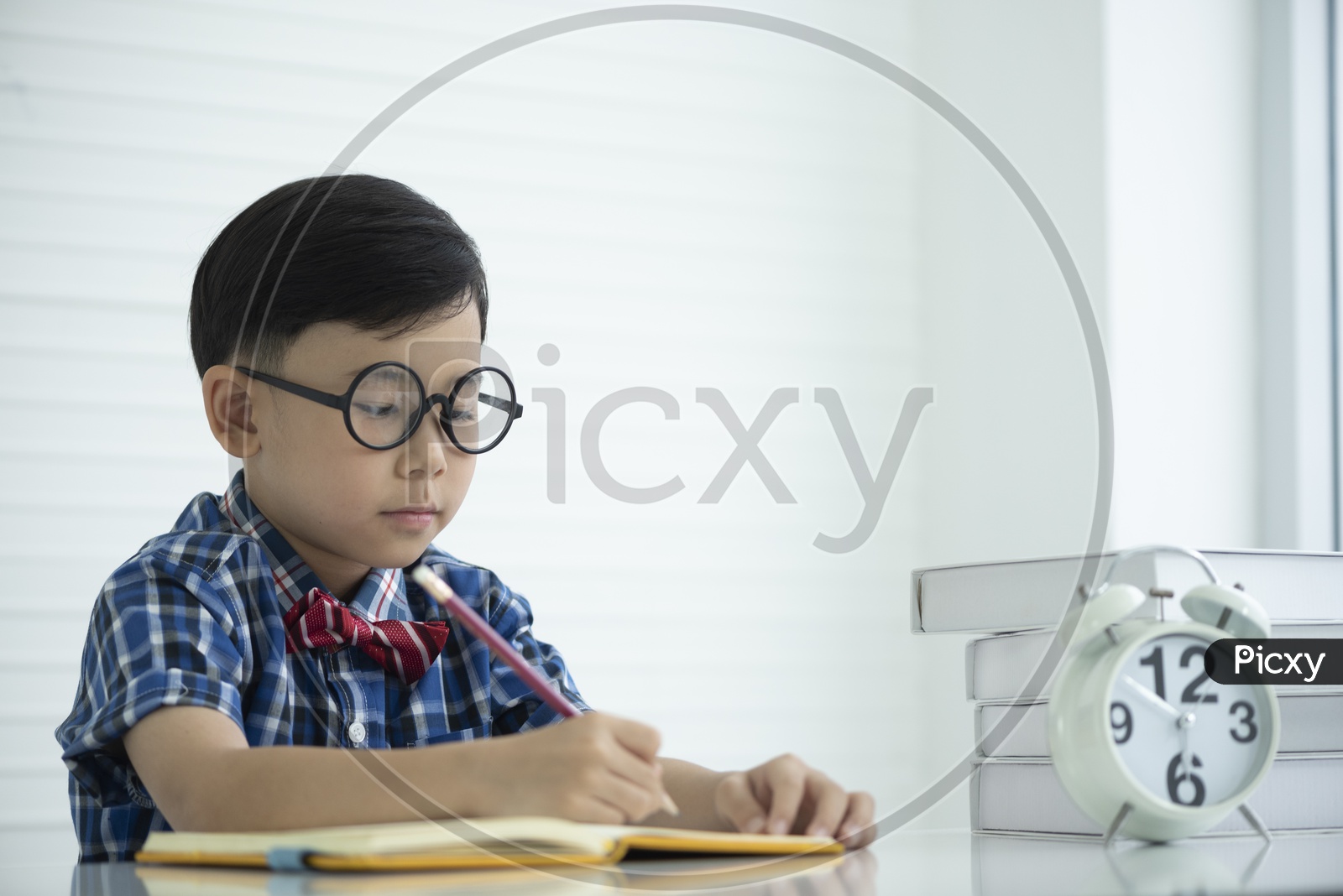 Portrait of a boy wearing spectacles and doing homework