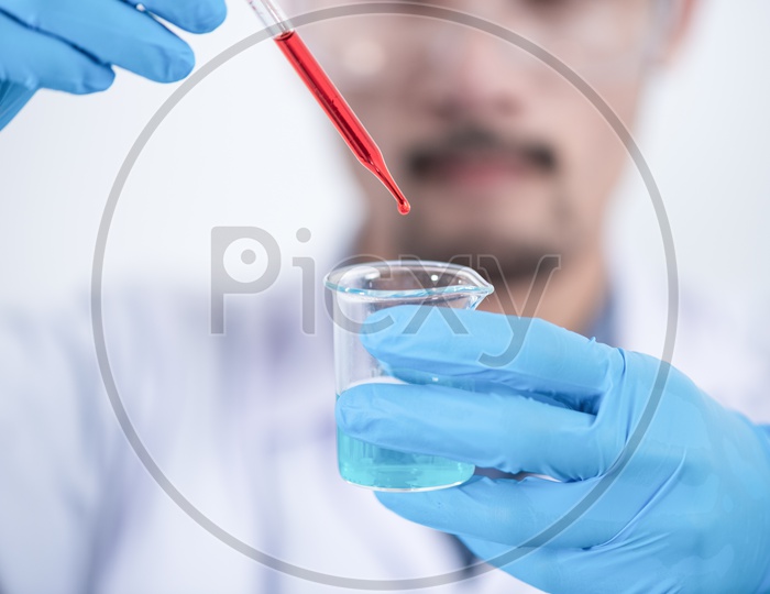 Asian Researcher with Safety gloves Dripping Blood into Glass Bottle Apparatus with Chemicals