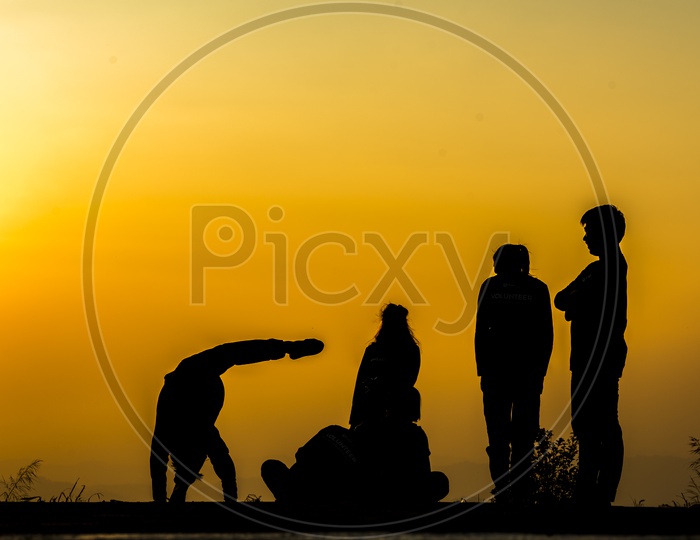 silhouette of people group practicing yoga on the beach at sunset