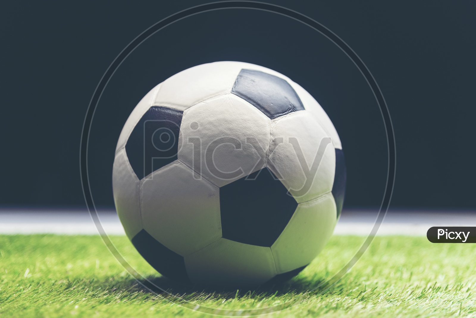Soccer ball on grass isolated on black background
