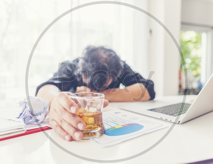 Depressed Or Stressed Business Man Addicted to Alcohol With Alcohol Glass At Office Desk