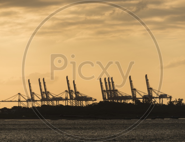 Heavy Cranes For Cargo Handling At Port Or Harbor With Sunset Sky