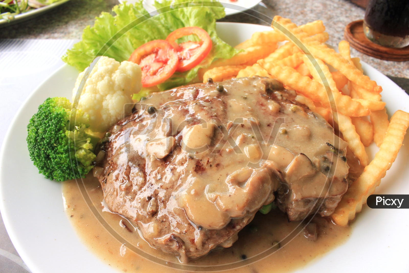 Beef steak with French Fries and Garnished with Leafy Vegetables