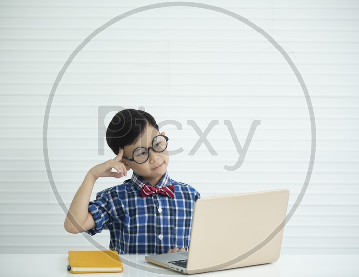 Portrait of a boy wearing spectacles studying with laptop