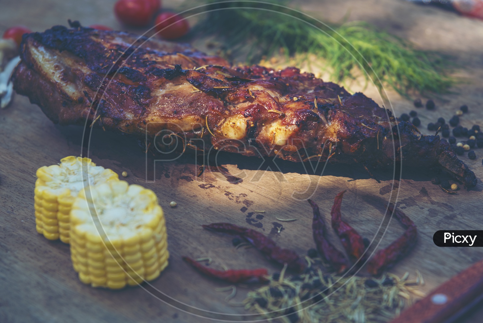 Fresh piece of pork ribs, Tomatoes, red chillis, pepper and herbs on a wooden cutting board