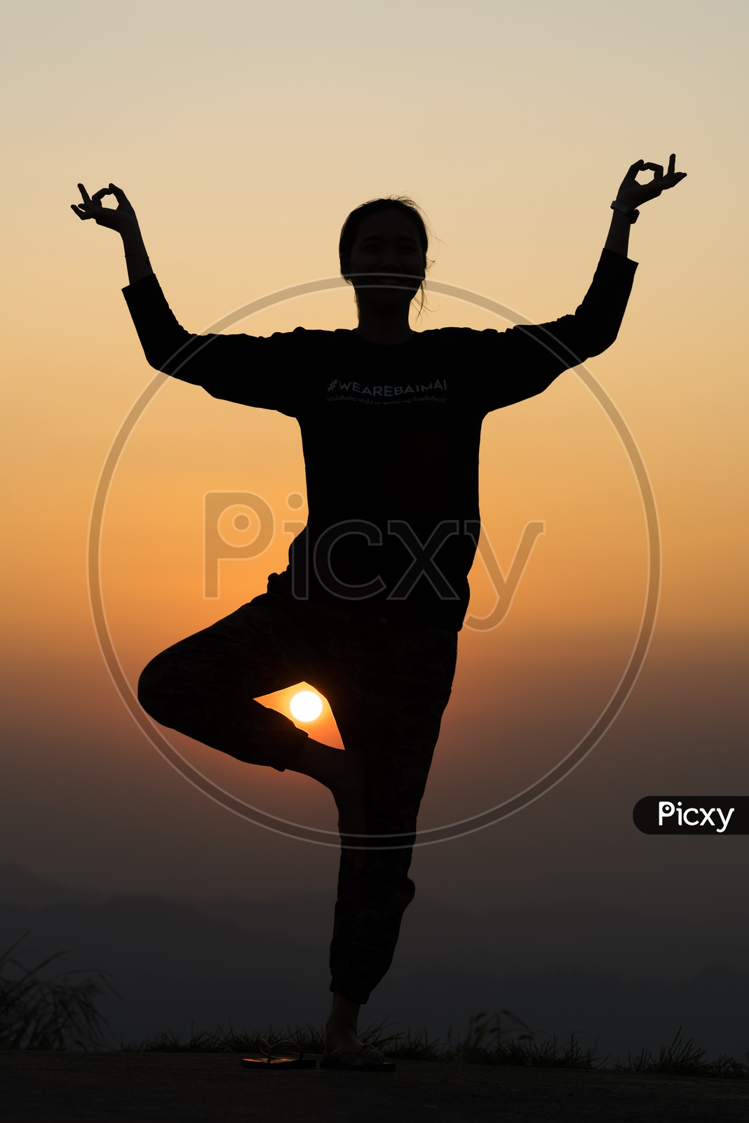 silhouette of people practicing yoga on the mountain at sunset