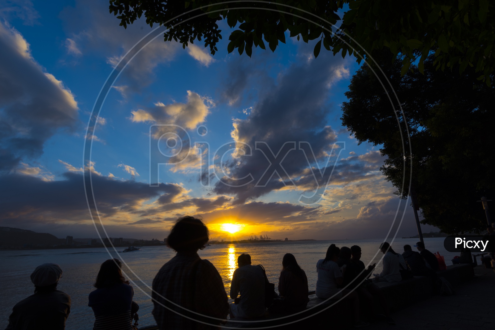 Silhouette Of People Sitting And Enjoying The Sunset Over A River