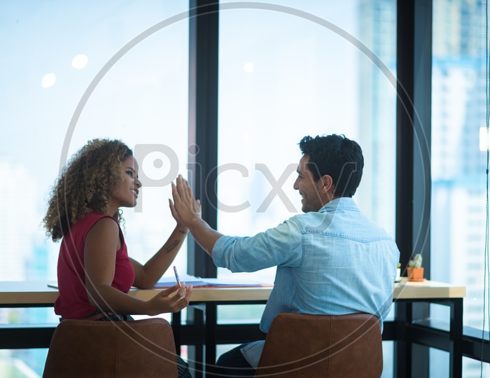 Young Coworkers in Office Discussing Business Strategy and giving High Five