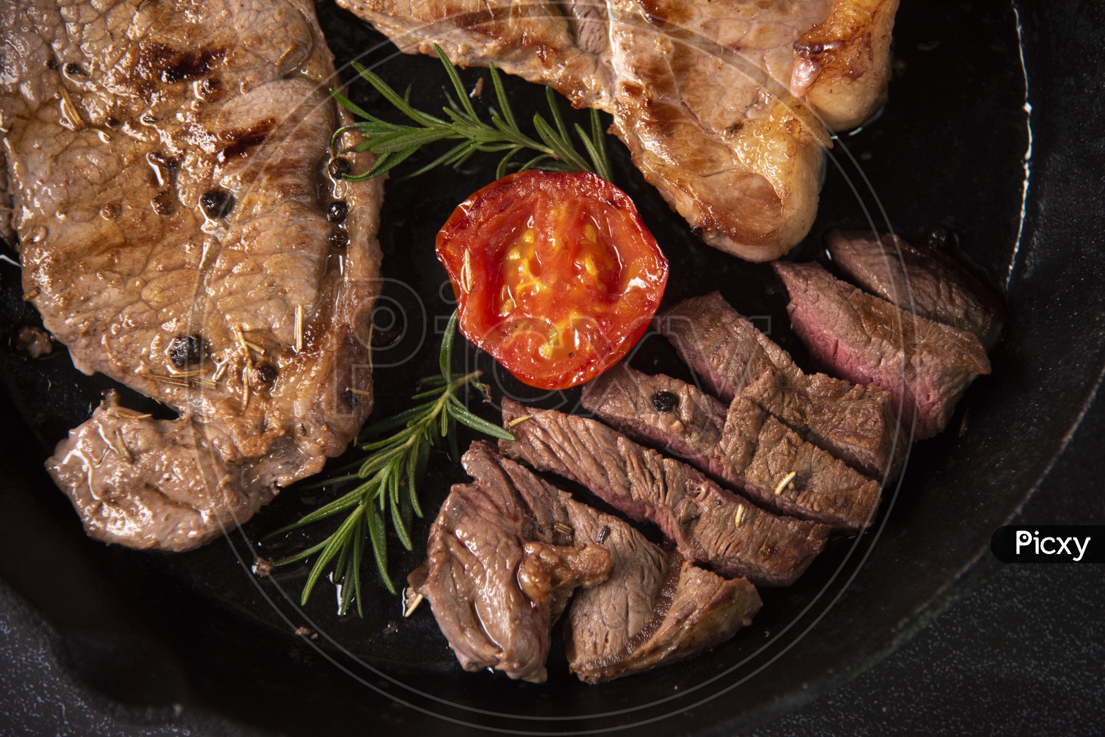 Grilled beef steaks with spices in black pan