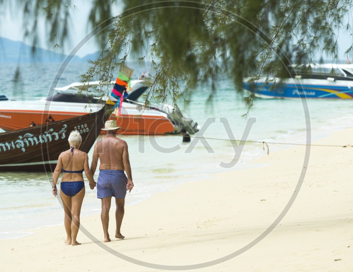 Tourist Couple Chilling in Phuket Beach With Tourist Boats in beach As Background