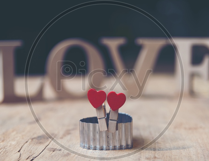 Heart shaped wooden clips in focus with letters of love in the background