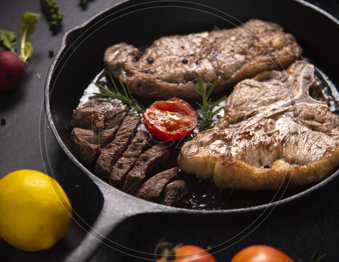 Grilled beef steaks with spices in black pan