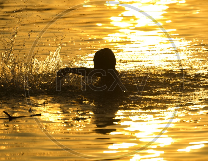 Silhouettes of a man Swimming during sunrise or sunset