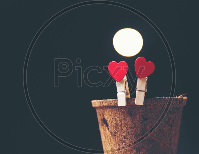 Heart shaped wooden clips on a wooden cup with black background