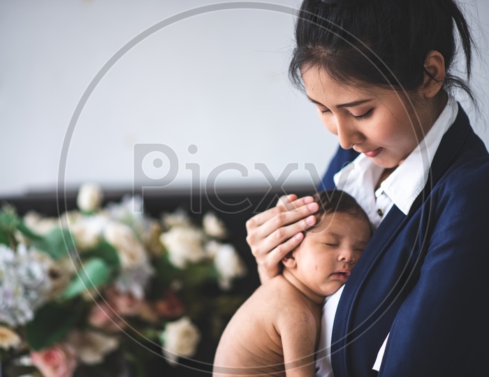 Portrait of Young Asian Businesswoman Taking Care of her Baby at Workplace