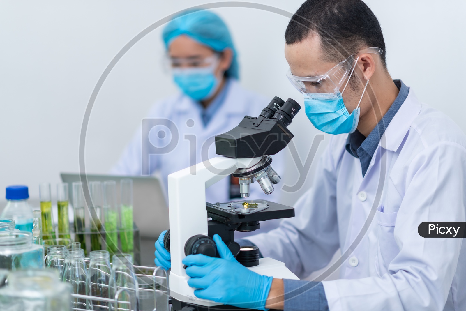 Asian Male Scientist Testing Algae fuel or BioFuel on Microscope at Chemical Laboratory