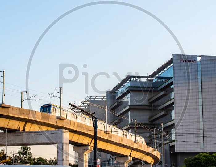Hyderabad Metro train Running On Tracks with trident Hotel in Background