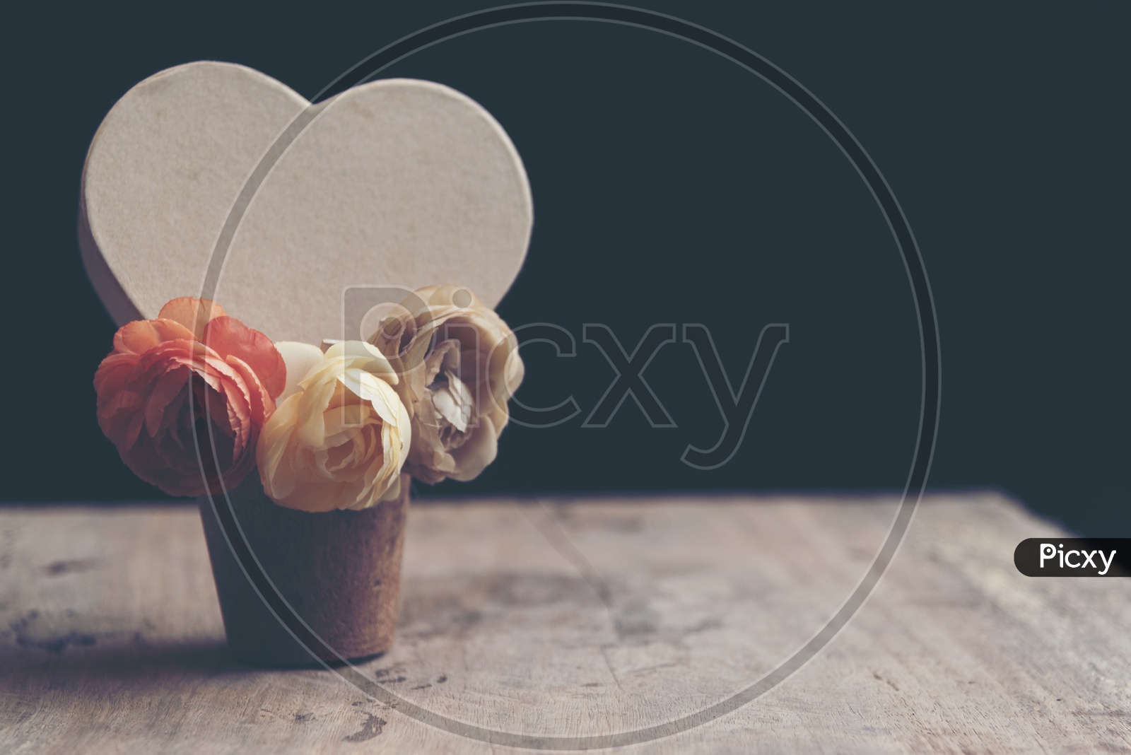 Heart shaped card with rose flowers in a wooden cup with black background