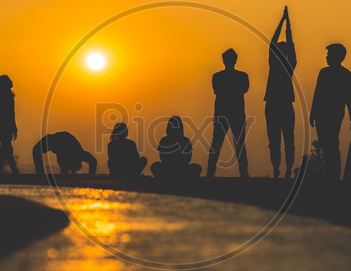 silhouette of  group  of People  practicing yoga on the beach at sunset