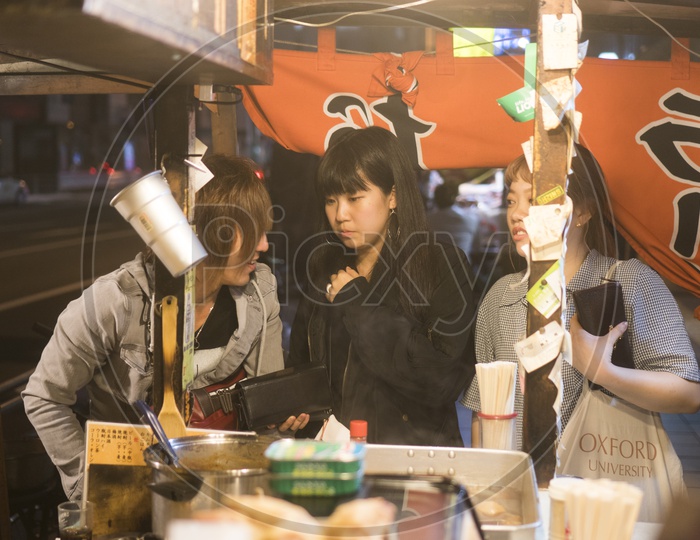 Japanese girls buying food at Yatai mobile food stall during night in Fukuoka, Kyushu, Japan