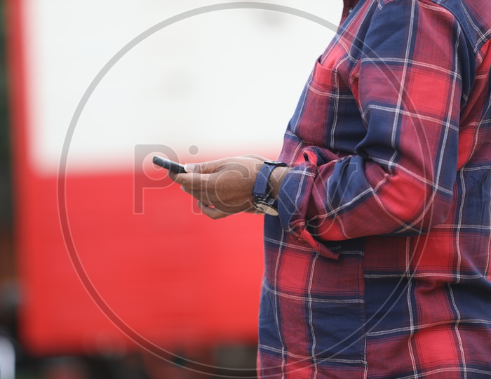 Indian Man wearing checkered shirt with mobile in hand