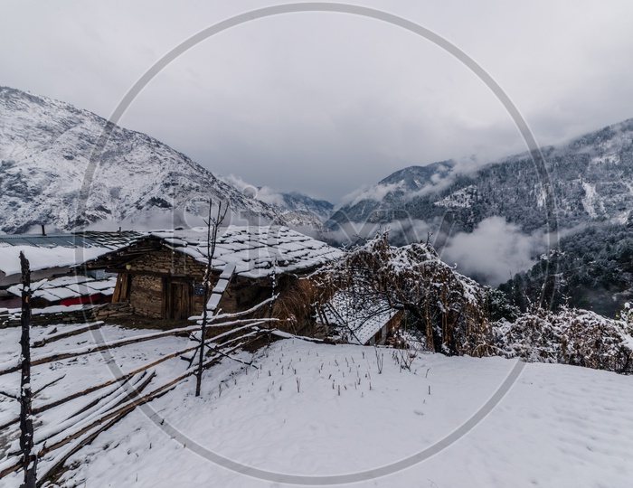Snow-covered wooden house with Snowy Himalayan Mountains in Background