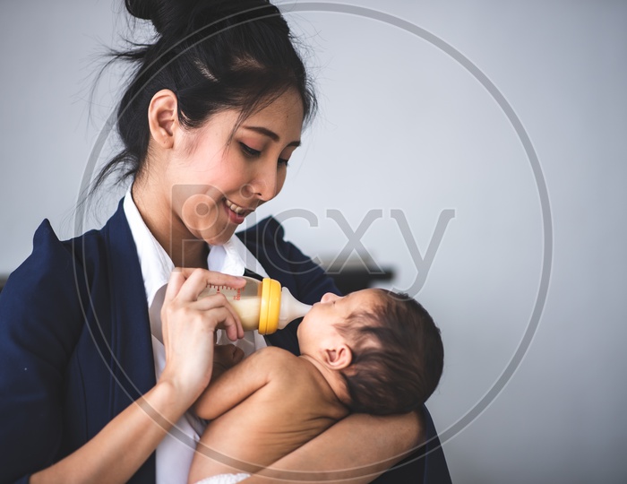 Young Asian Mother Feeding her baby at the workplace