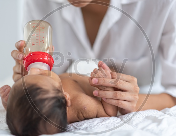 Mother feeding milk to the baby with a baby bottle