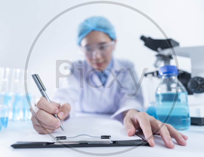Asian Woman Scientist or Medical Student writing down Test Results at Laboratory