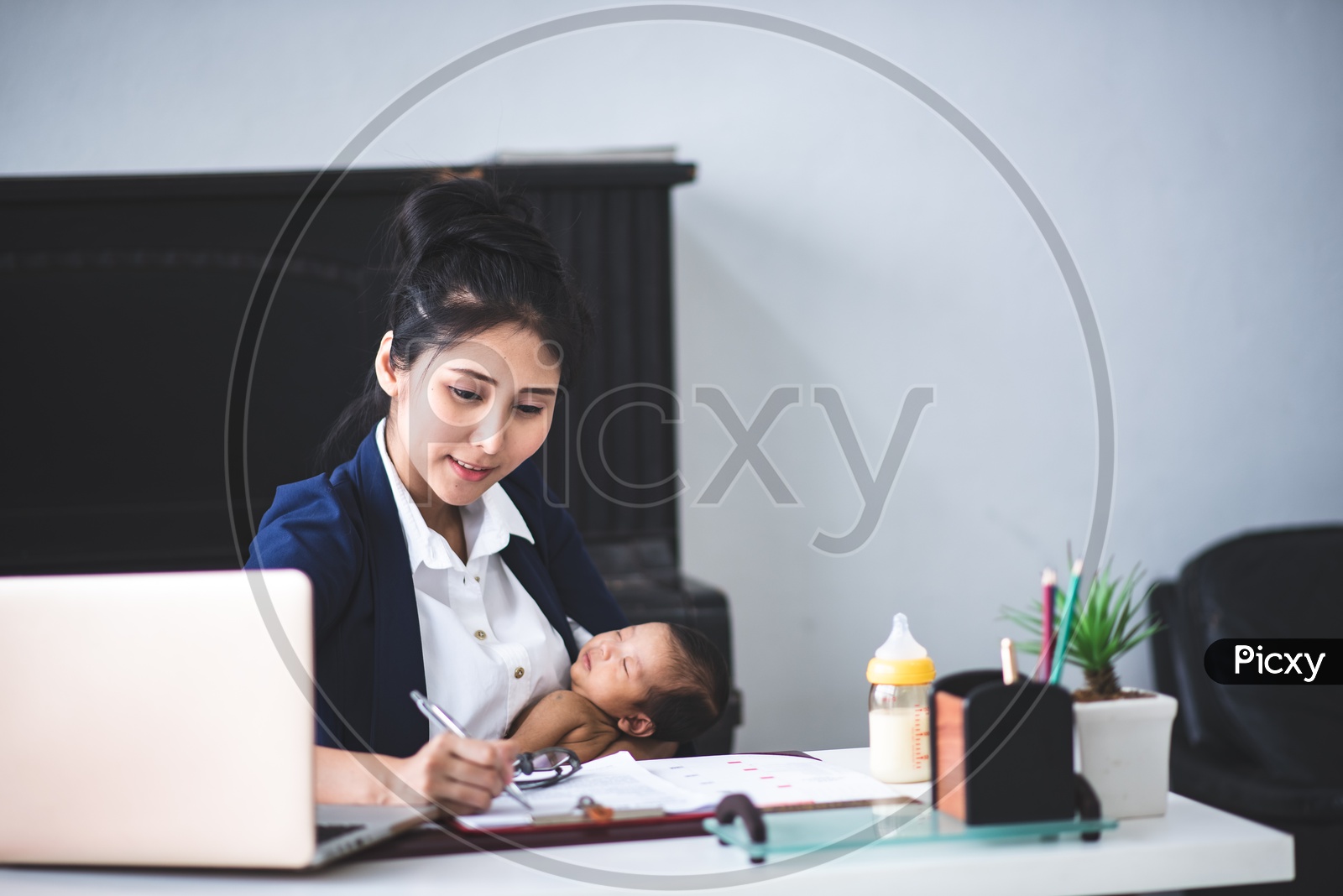 Young Asian Businesswoman working in Office and taking care of her Baby